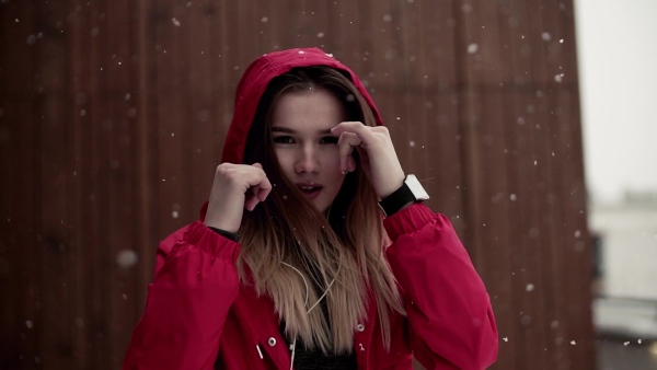 A young girl or woman with earphones doing exercise outdoors in winter, boxing. Slow motion.