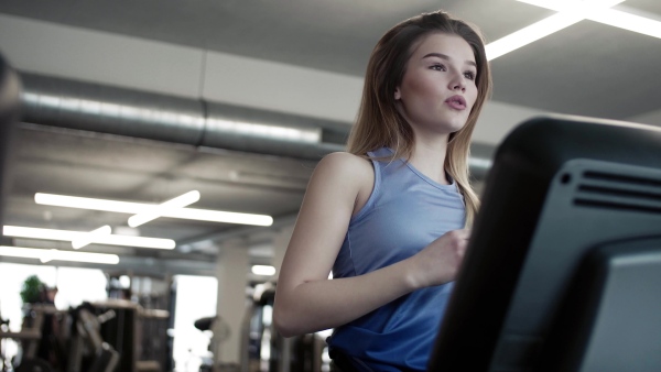 A portrait of a beautiful young girl or woman doing cardio workout in a gym.