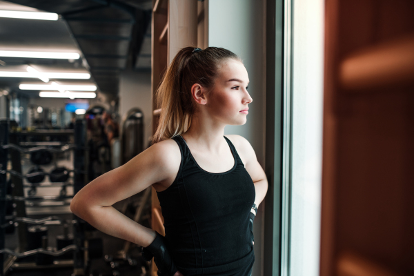 A portrait of a beautiful young girl or woman standing in a gym.