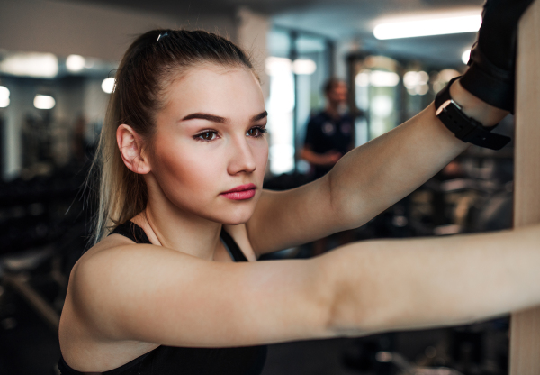 A portrait of a beautiful young girl or woman standing in a gym.