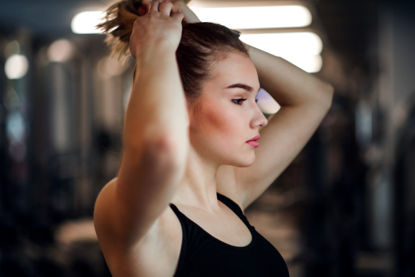 A portrait of a beautiful young girl or woman standing in a gym.