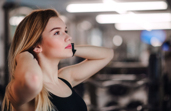 A portrait of a beautiful young girl or woman standing in a gym. Copy space.