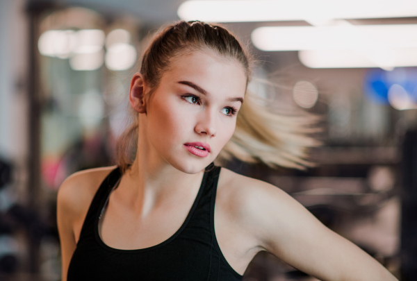 A portrait of a beautiful young girl or woman standing in a gym.