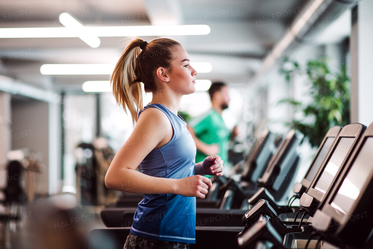 A portrait of a beautiful young girl or woman doing cardio workout in a gym.