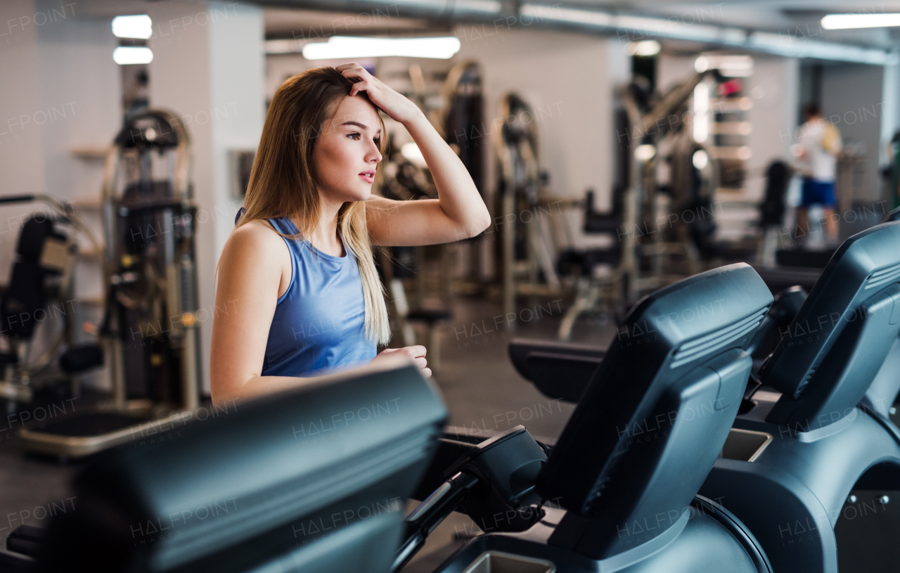 A portrait of a beautiful young girl or woman doing cardio workout in a gym.