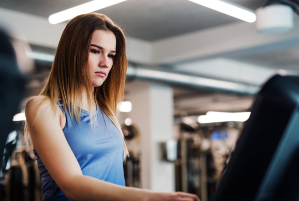 A portrait of a beautiful young girl or woman doing cardio workout in a gym.