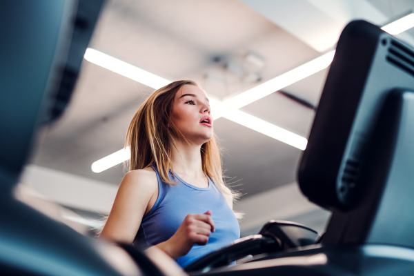 A portrait of a beautiful young girl or woman doing cardio workout in a gym.