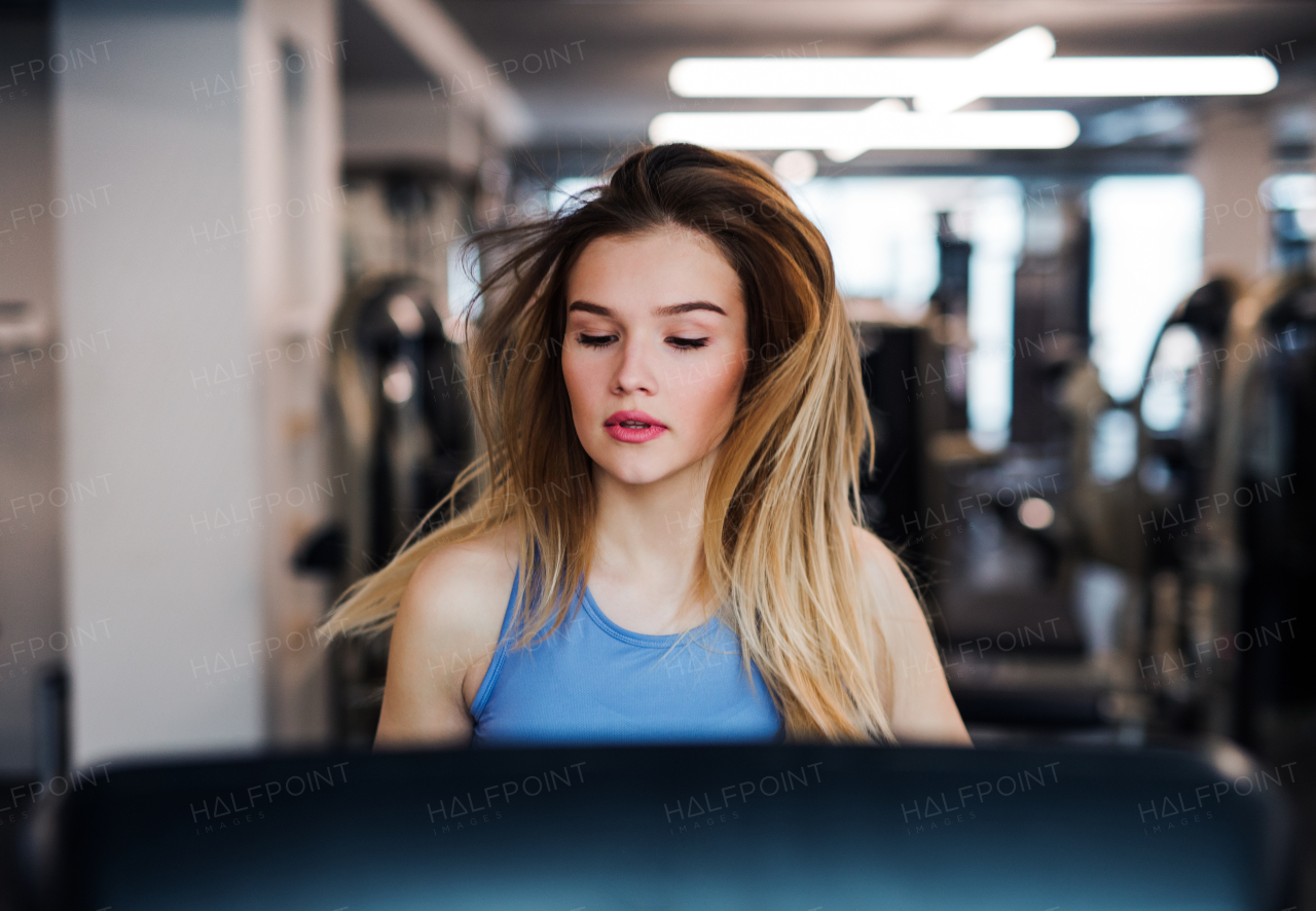 A portrait of a beautiful young girl or woman doing cardio workout in a gym.