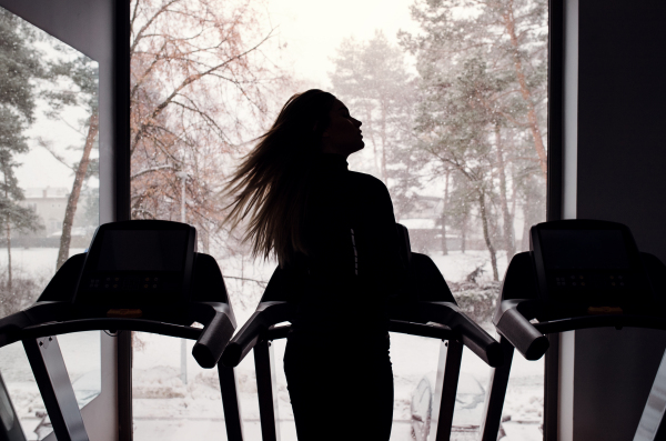 A rear view of a silhouette of young girl or woman doing cardio workout in a gym.