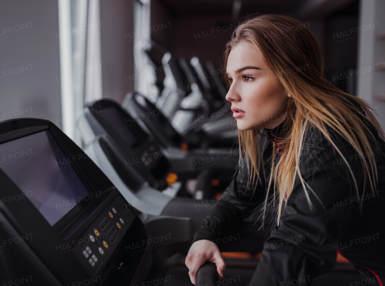 A side view of a beautiful young girl or woman doing cardio workout in a gym.