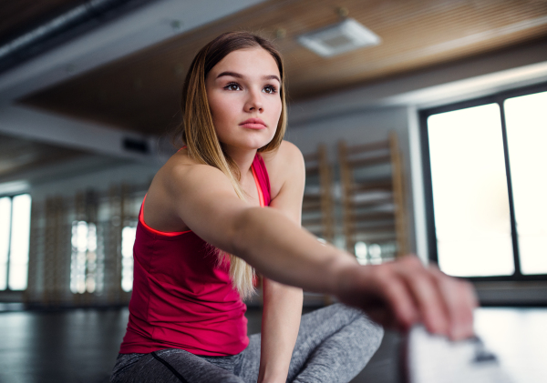 A portrait of a beautiful young girl or woman doing exercise in a gym.