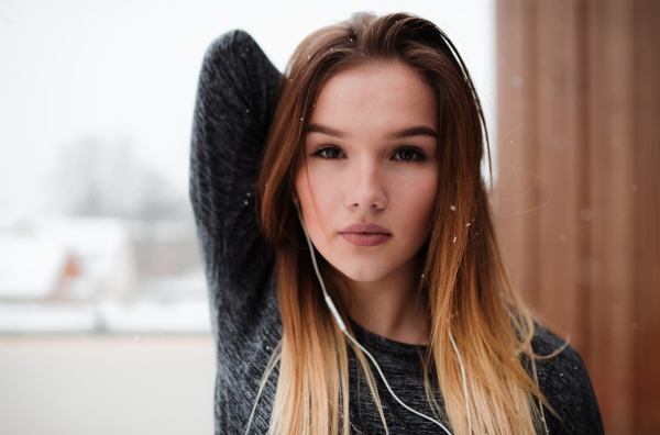 A portrait of young girl or woman with earphones doing stretching outdoors on a terrace. Copy space.