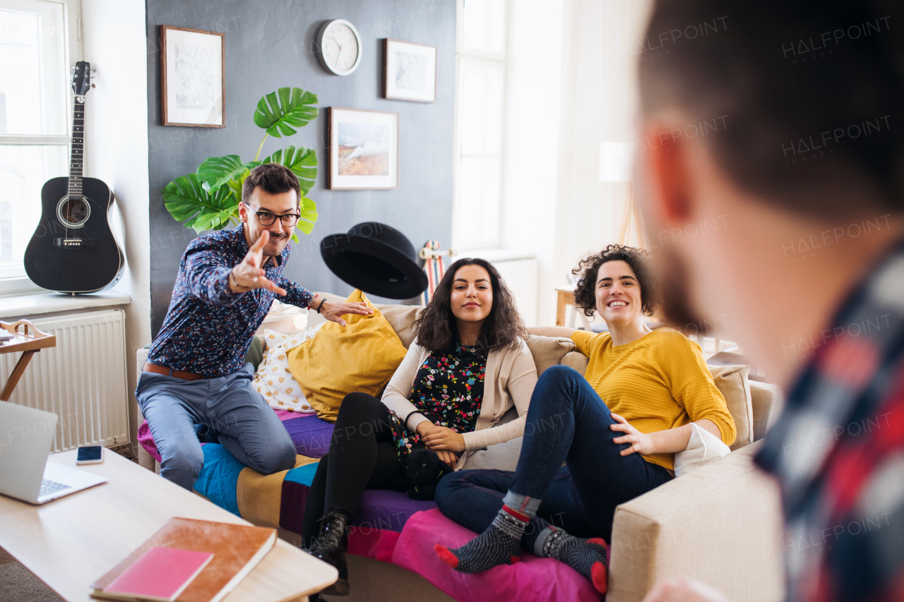 A group of young cheerful friends indoors at home, having fun. A house sharing concept.