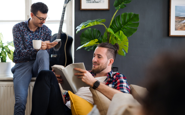 A group of young cheerful friends relaxing indoors, house sharing concept.