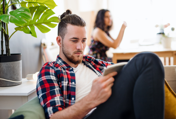 Two young cheerful friends relaxing indoors, house sharing concept.