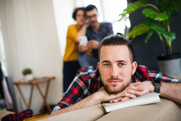 A portrait of young man with book indoors, sharing house with friends concept.