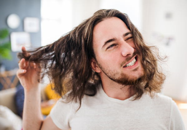 A portrait of young bearded man with long hair indoors, a close-up.