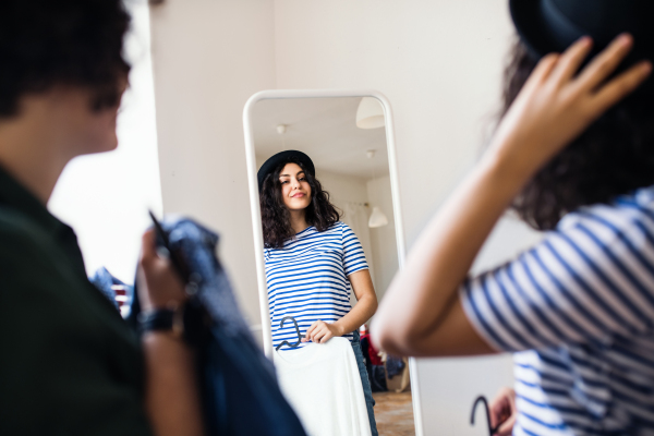 Young female friends trying on clothes indoors, house sharing concept.