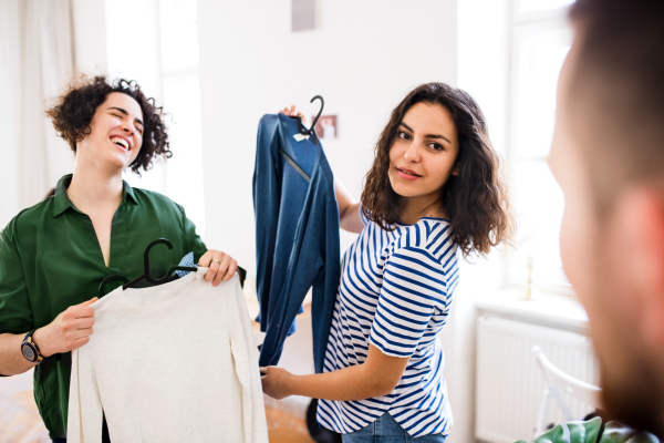 A group of young friends with clothes indoors, having fun. A house sharing concept.