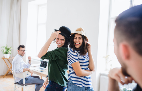 A group of young friends with hats indoors, having fun. A house sharing concept.