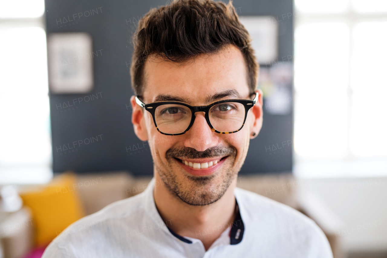 A portrait of young laughing man indoors, looking at camera. A close-up.