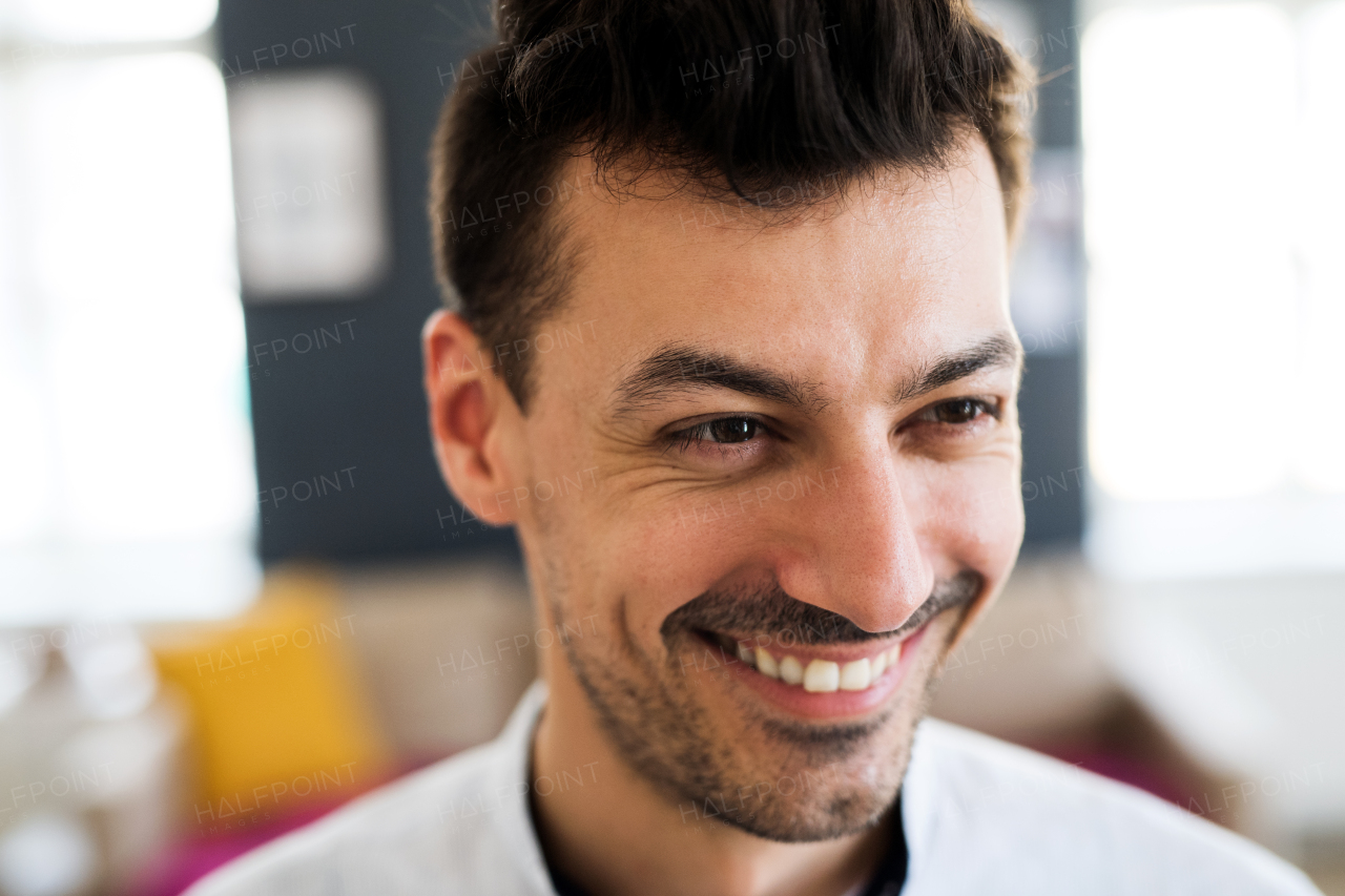 A portrait of young laughing man indoors, a close-up.