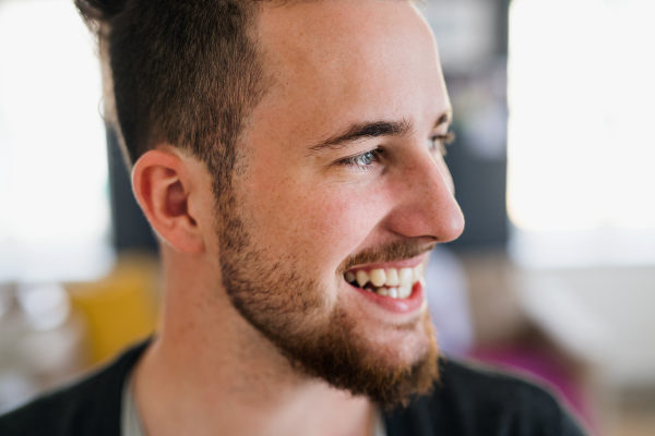 A portrait of young hipster bearded man indoors, a close-up.