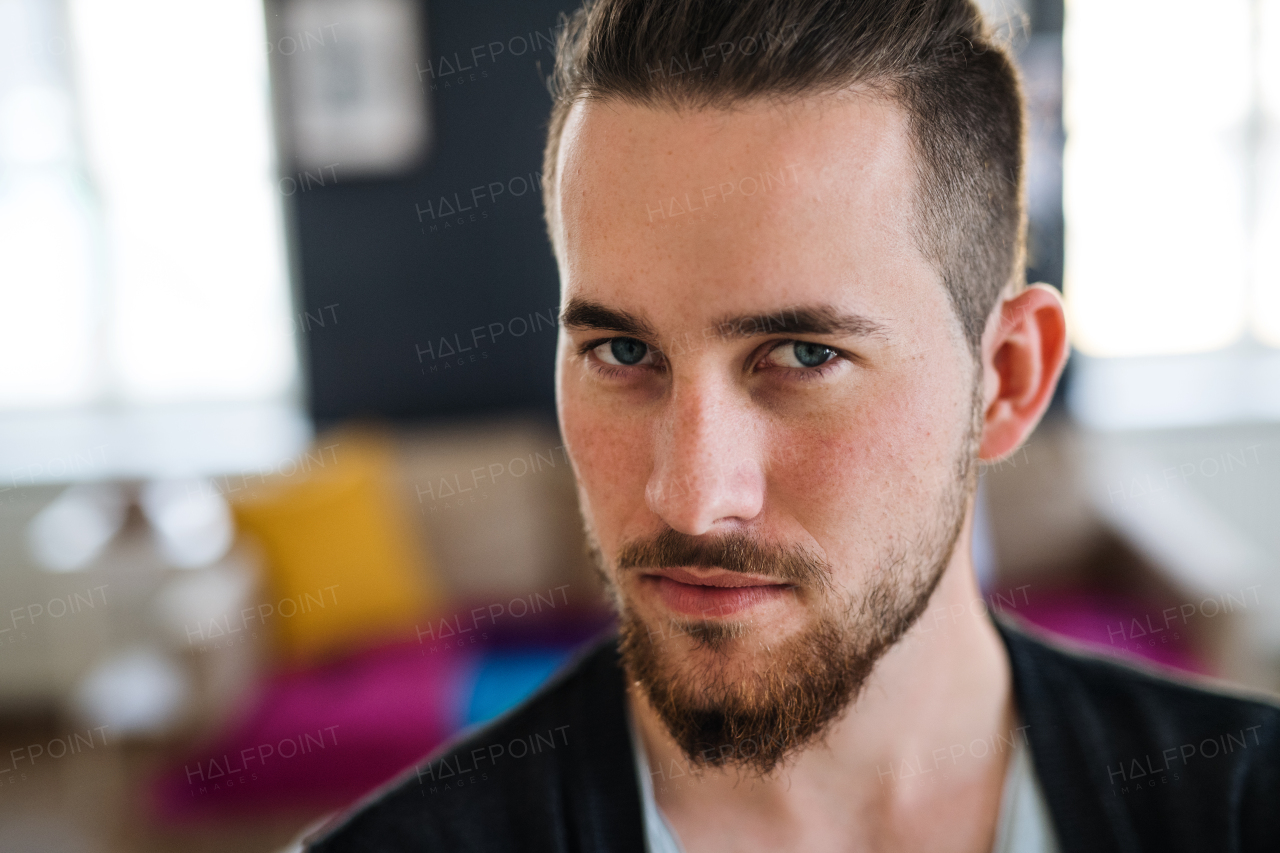 A portrait of young bearded man indoors, a close-up.