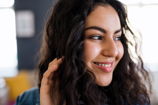 A portrait of young woman with wavy hair indoors, a close-up.