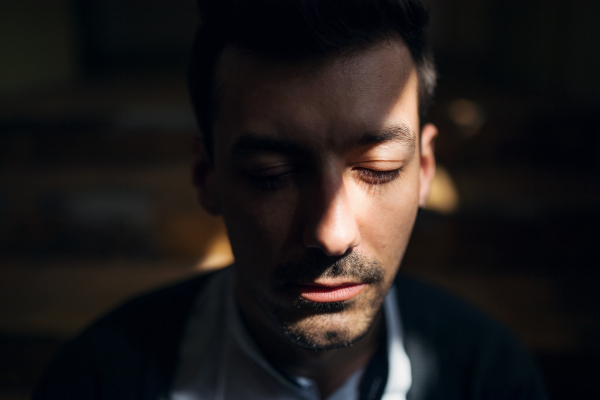 A front view of portrait of young bearded man indoors, a close-up.