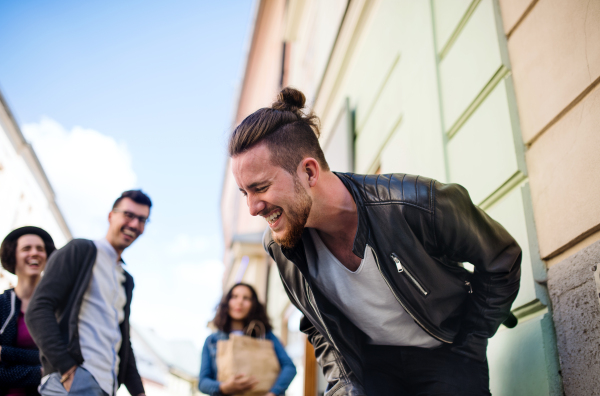 A group of young friends walking outdoor in town, talking and having fun.