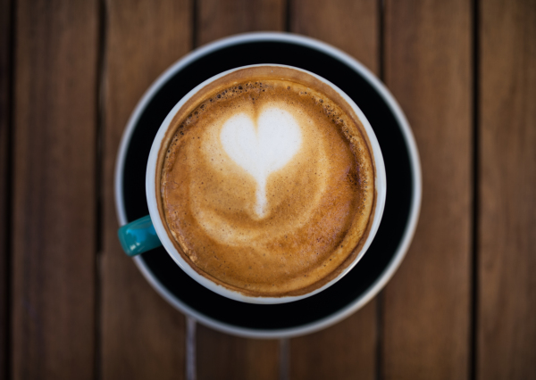 A top view of cappuccino coffee with cream on a wooden table.