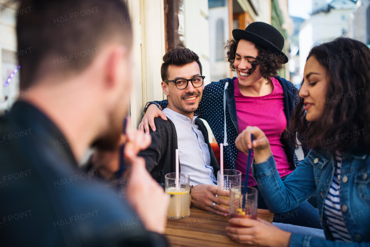 A group of young cheerful friends sitting in an outdoor cafe, talking.