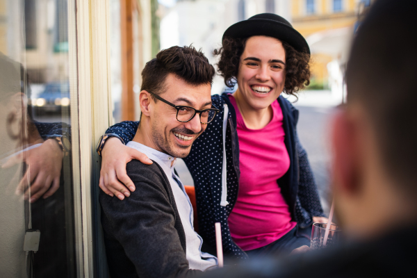 A group of young cheerful friends sitting in an outdoor cafe, talking.