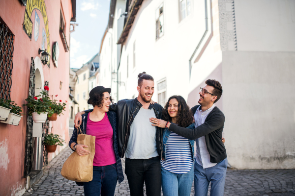 A group of young friends walking outdoor in town, talking and having fun.