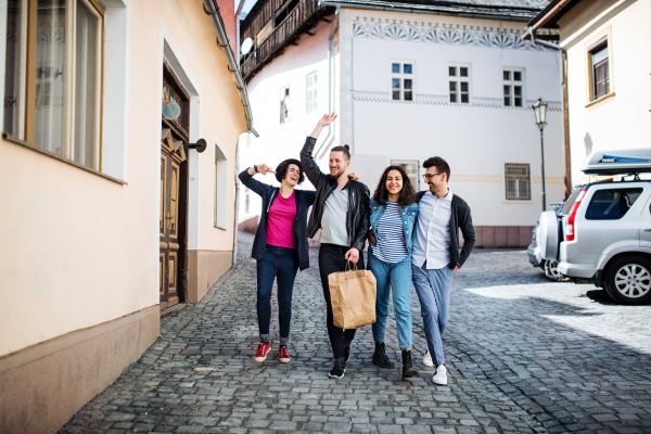 A group of young friends walking outdoor in town, talking and having fun.