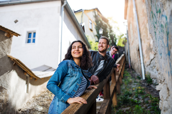 A portrait of group of young cheerful friends standing outdoors on staircase in town.