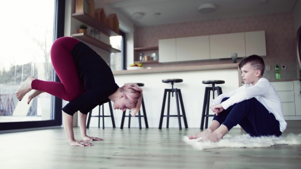 A happy young woman with small son playing on the floor, having fun.