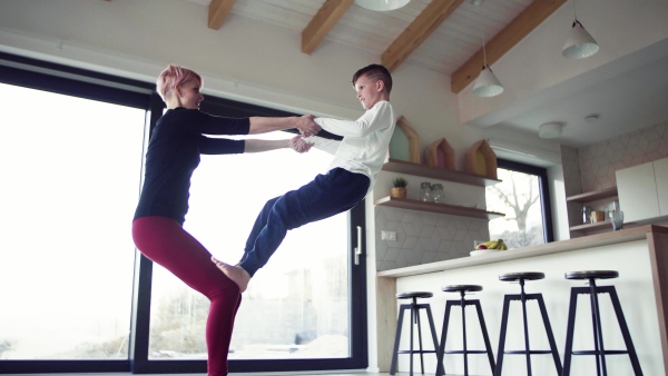 A young mother doing exercise with small son indoors at home, having fun.