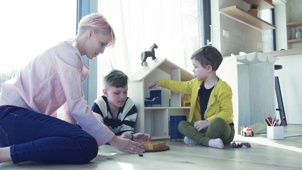 A young woman with two children playing board games on the floor. Slow motion.