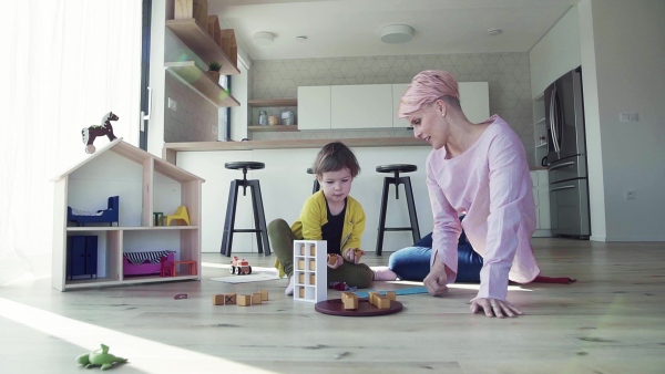 A young woman and small daughter playing on the floor at home. Slow motion.