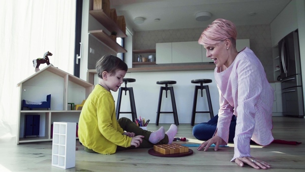 A young woman and small daughter playing on the floor at home. Slow motion.