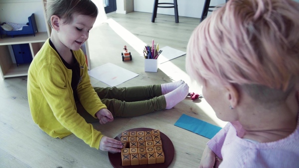 A young woman and small daughter playing on the floor at home. Slow motion.