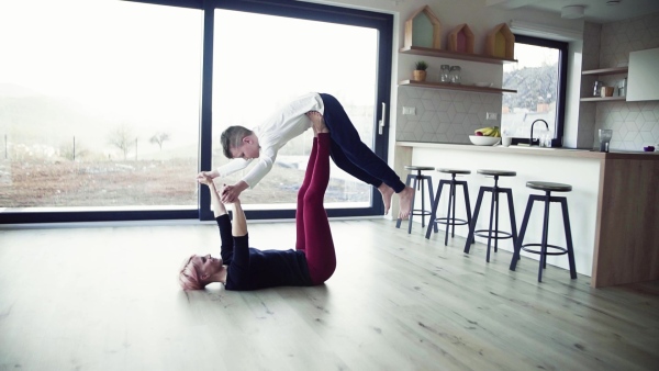 A happy young woman with small son playing on the floor, having fun. Slow motion.