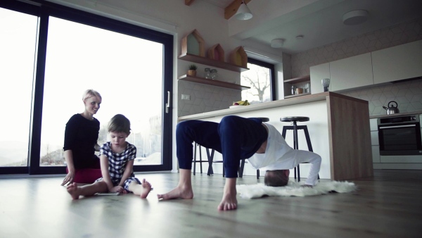 A happy young woman with two children playing on the floor, having fun. Slow motion.