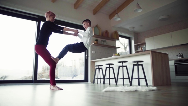 A happy young woman with small son playing indoors at home, having fun. Slow motion.