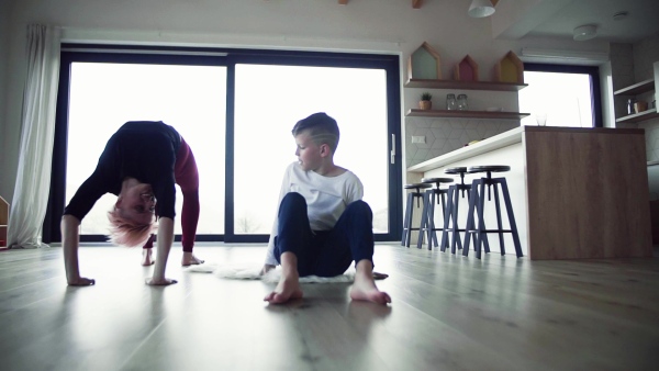 A young mother doing exercise with small son indoors at home. Slow motion.