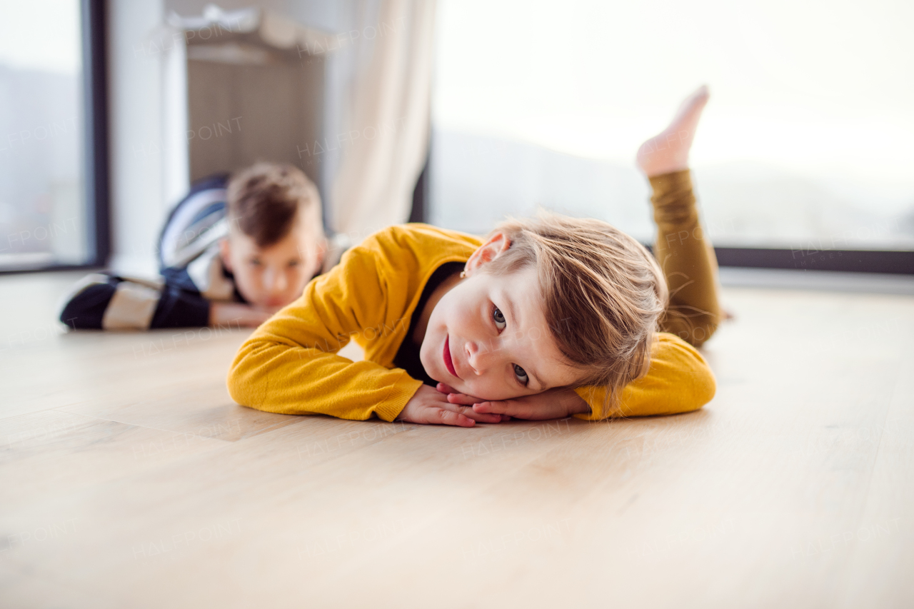 Portrait of two happy children lying on floor indoors at home.