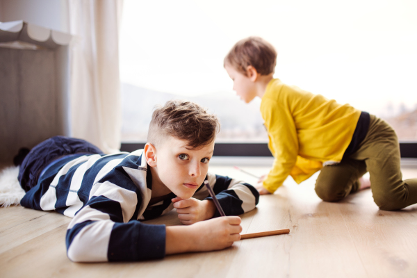 Two happy small children playing at home, drawing.