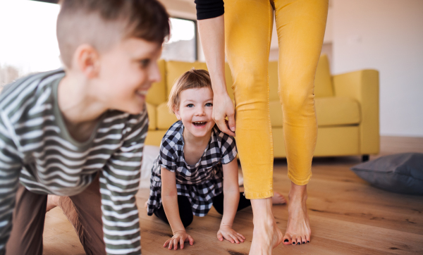 A midsection of young woman with two children playing at home, having fun.